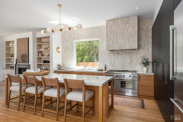 kitchen with a center island, high end appliances, a breakfast bar, sink, and built in shelves