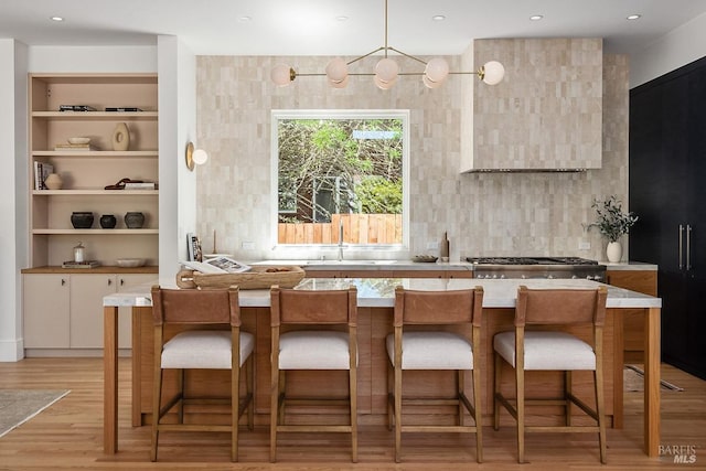 kitchen with sink, white cabinets, light hardwood / wood-style floors, decorative backsplash, and a breakfast bar