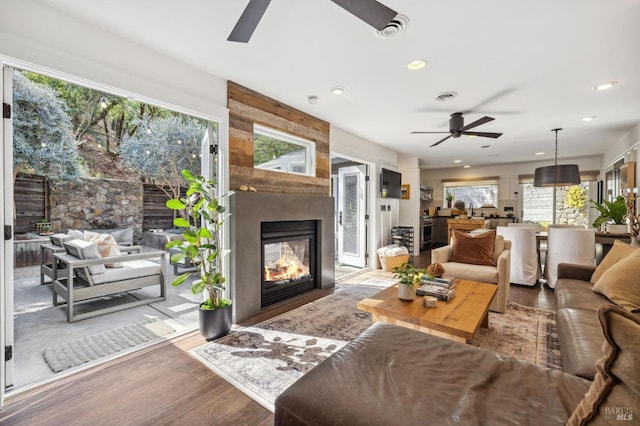 living room with a multi sided fireplace, hardwood / wood-style flooring, and ceiling fan