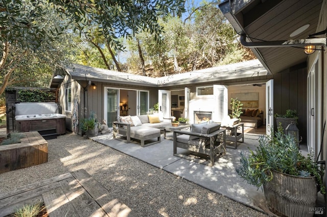 view of patio featuring area for grilling, a hot tub, and an outdoor living space with a fireplace