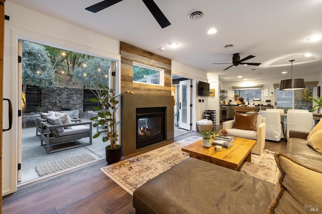 living room featuring a fireplace, ceiling fan, and dark hardwood / wood-style flooring