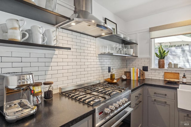 kitchen with gray cabinets, island range hood, high end stainless steel range oven, and decorative backsplash