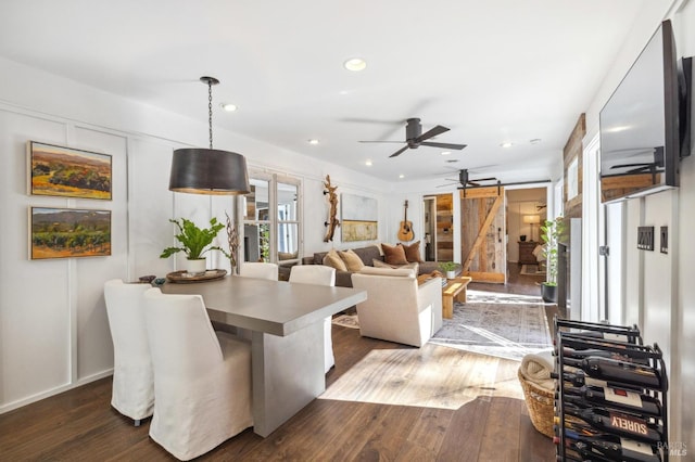 living room featuring ceiling fan, a barn door, and dark hardwood / wood-style floors