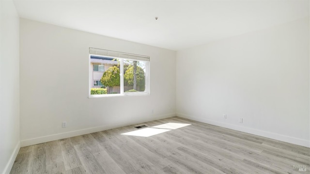 unfurnished room with baseboards, light wood-style flooring, and visible vents