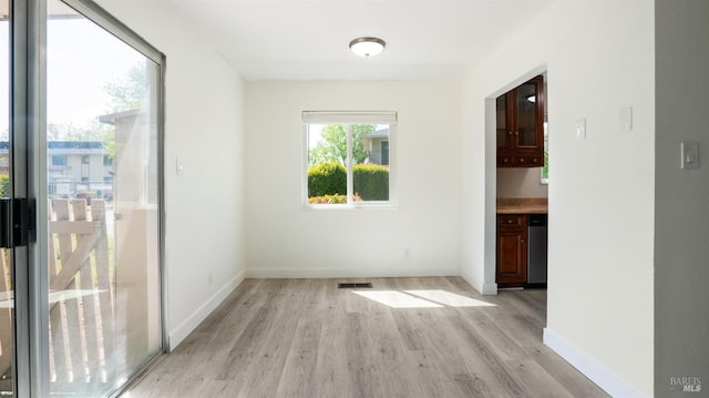 unfurnished dining area with baseboards and light wood finished floors