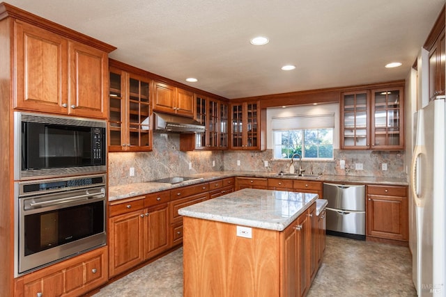 kitchen featuring light stone counters, black appliances, decorative backsplash, a kitchen island, and sink