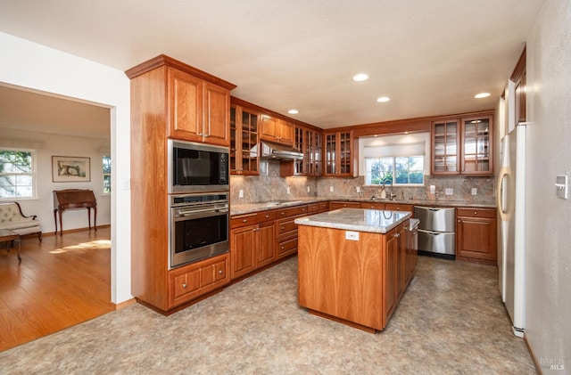 kitchen featuring decorative backsplash, black appliances, a wealth of natural light, and a center island