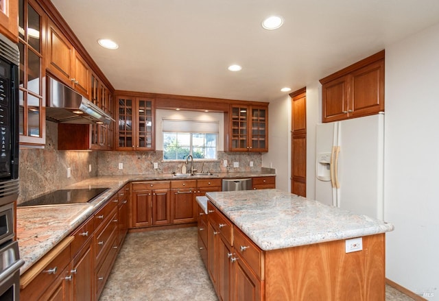 kitchen with dishwasher, light stone countertops, black electric cooktop, a kitchen island, and sink