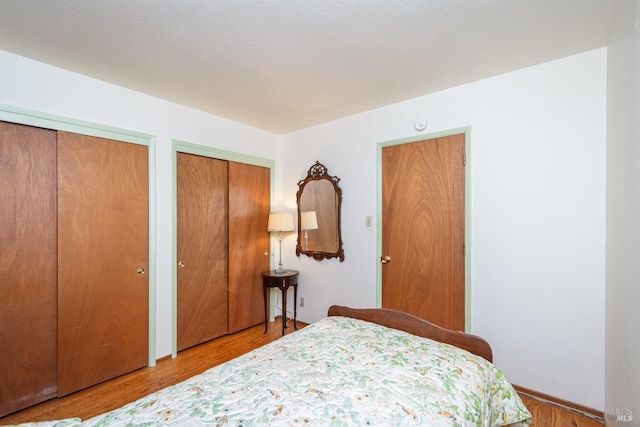 bedroom with multiple closets and light hardwood / wood-style floors