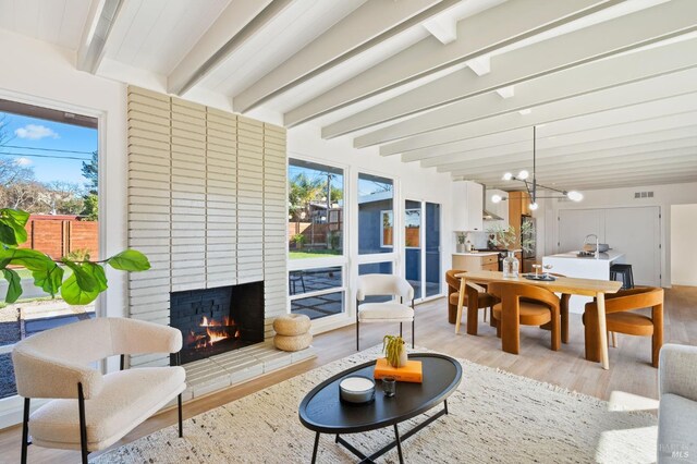 sunroom / solarium with a fireplace, a chandelier, and beamed ceiling