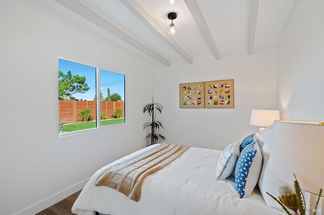 bedroom with baseboards, beam ceiling, and wood finished floors