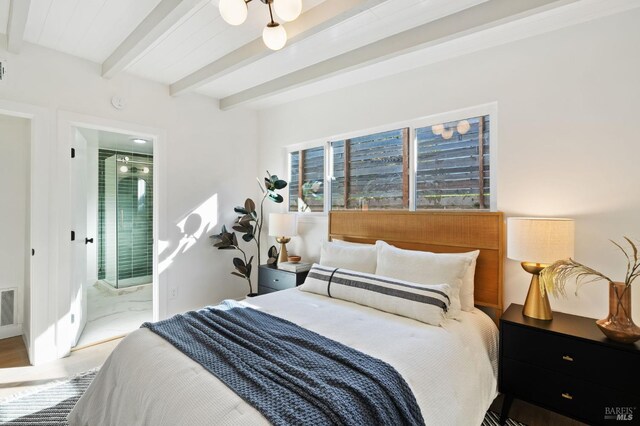 bedroom featuring hardwood / wood-style flooring, beam ceiling, and connected bathroom