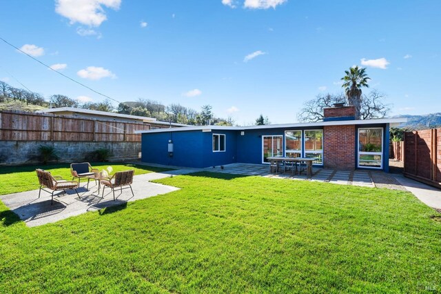 back of house with a patio and a yard