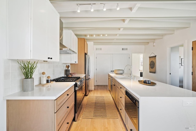 kitchen with decorative backsplash, beamed ceiling, light countertops, stainless steel appliances, and a sink