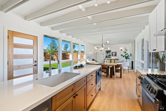 kitchen with sink, light hardwood / wood-style flooring, white cabinets, and beam ceiling