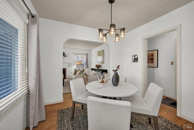 dining area featuring a brick fireplace, light hardwood / wood-style floors, and a notable chandelier