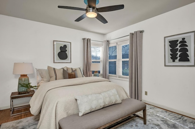 bedroom featuring baseboards, wood finished floors, and a ceiling fan