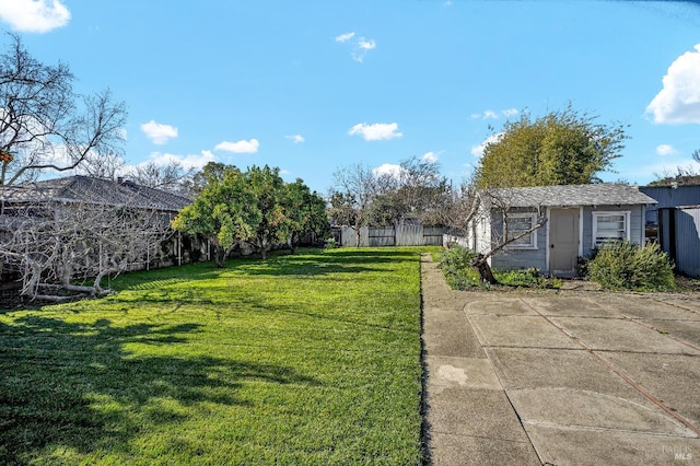 view of yard with fence, an outdoor structure, and a storage unit