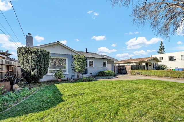 view of front facade featuring a front lawn, driveway, a chimney, an attached garage, and fence