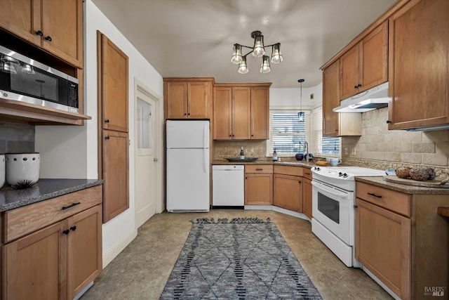 kitchen with brown cabinets, under cabinet range hood, tasteful backsplash, white appliances, and dark countertops