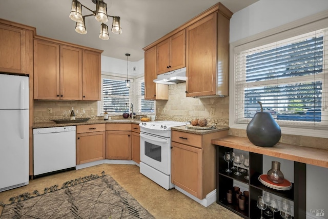 kitchen with white appliances, decorative light fixtures, under cabinet range hood, backsplash, and a sink