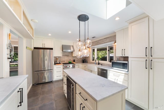 kitchen featuring a center island, beverage cooler, a skylight, wall chimney range hood, and premium appliances