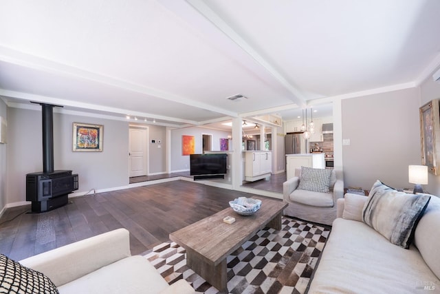 living room with hardwood / wood-style flooring, crown molding, a wood stove, and beamed ceiling