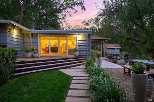 back house at dusk featuring a patio