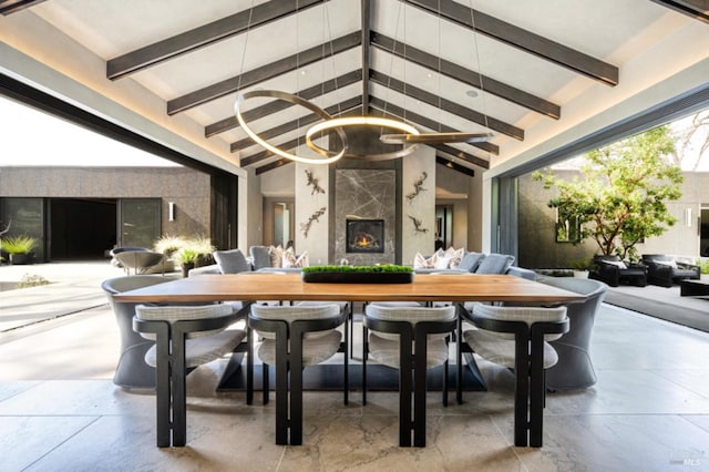 dining room with a chandelier, beam ceiling, high vaulted ceiling, and a premium fireplace