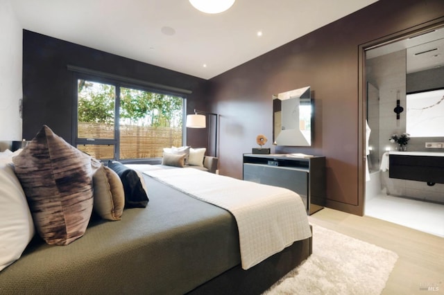 bedroom with light hardwood / wood-style floors and ensuite bath