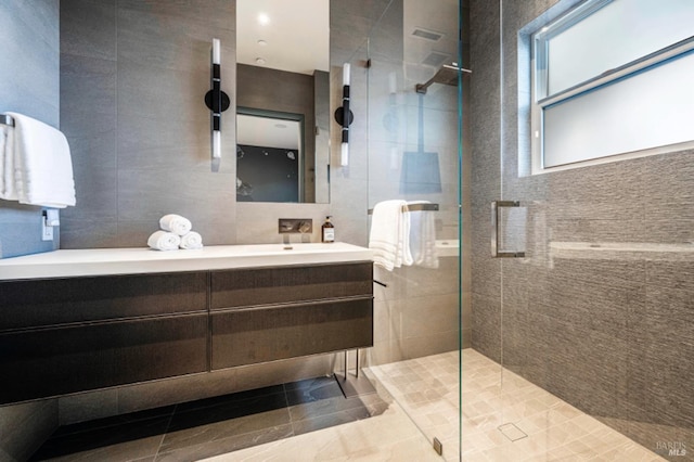 bathroom featuring tiled shower, tile walls, and vanity