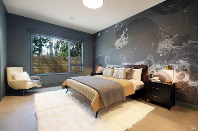 bedroom featuring ensuite bath and light hardwood / wood-style flooring