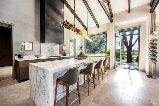 kitchen featuring light stone countertops, a wealth of natural light, a center island, and beamed ceiling