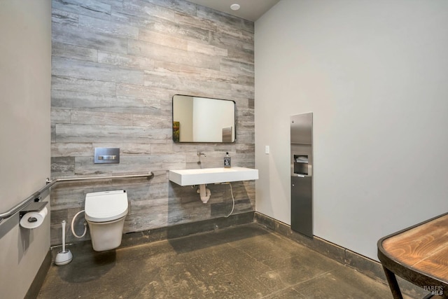 half bathroom with baseboards, toilet, an accent wall, granite finish floor, and a sink