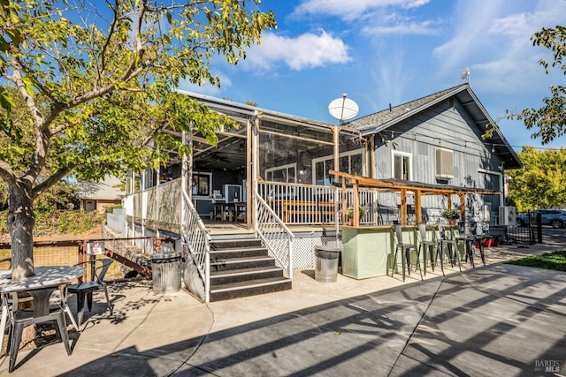 rear view of property featuring exterior bar, a deck, stairway, and a patio area