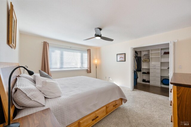 bedroom with a spacious closet, ceiling fan, a closet, and light carpet