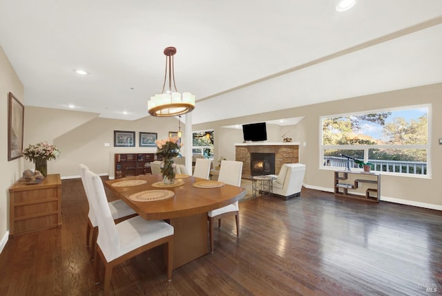 dining room with dark wood-type flooring and a fireplace