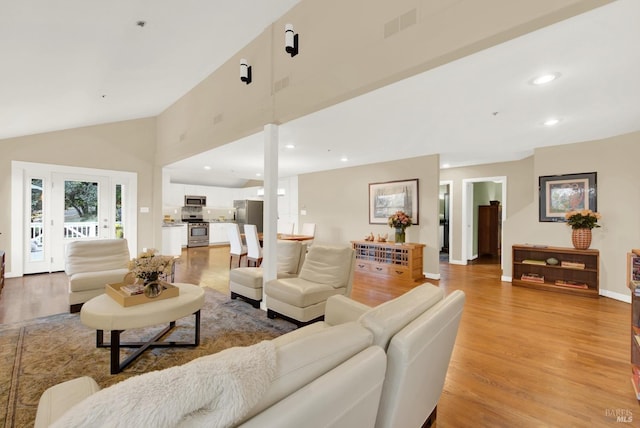 living room with high vaulted ceiling and light hardwood / wood-style flooring