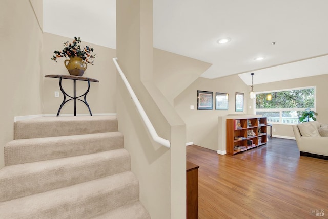 stairway featuring hardwood / wood-style flooring and lofted ceiling