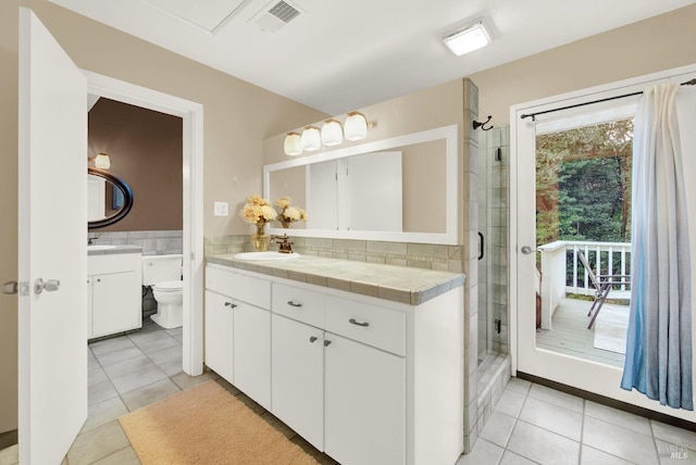 bathroom featuring tile patterned floors, vanity, toilet, and an enclosed shower