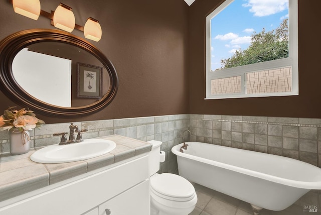 bathroom featuring a tub to relax in, tile patterned flooring, vanity, and tile walls