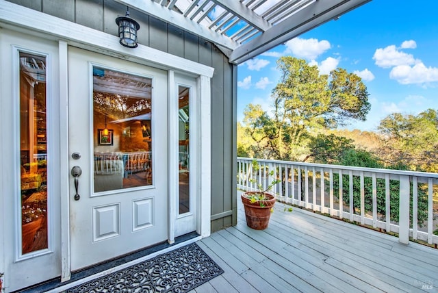 entrance to property featuring a wooden deck and a pergola