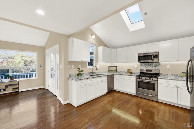 kitchen featuring lofted ceiling with skylight, dark hardwood / wood-style floors, white cabinetry, stainless steel appliances, and light stone countertops