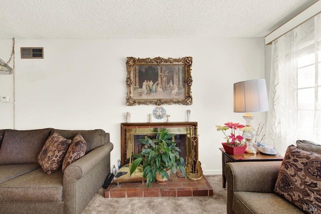 living area with carpet floors, visible vents, a fireplace with raised hearth, and a textured ceiling