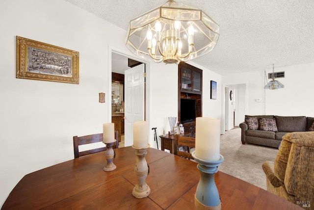 dining area featuring carpet floors, a textured ceiling, visible vents, and a notable chandelier