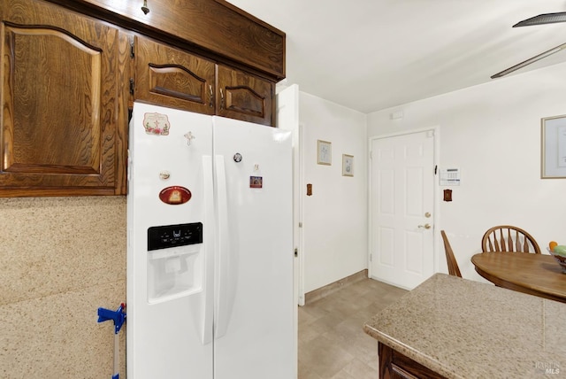 kitchen featuring a ceiling fan, white refrigerator with ice dispenser, and light floors