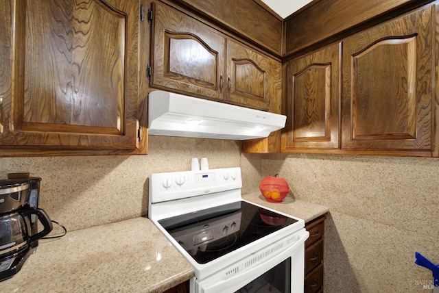 kitchen featuring electric stove, brown cabinetry, and under cabinet range hood