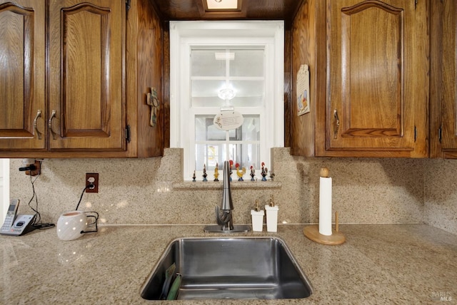 kitchen with decorative backsplash, brown cabinetry, and a sink