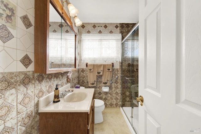 bathroom with toilet, vanity, tile walls, and a shower stall