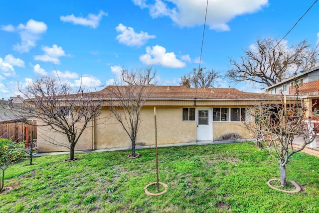 back of property with fence, a lawn, and stucco siding